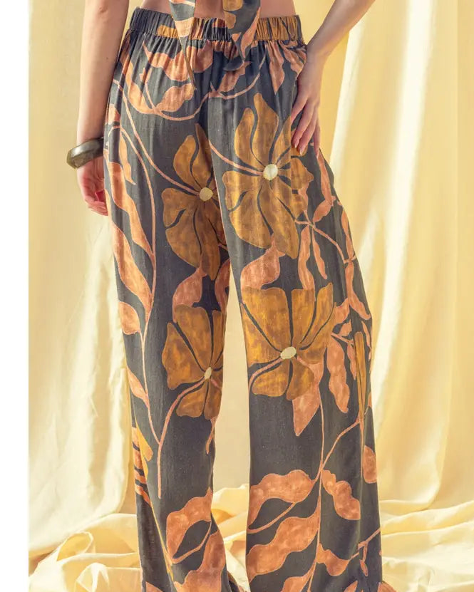 Floral-patterned pants worn by a person against a beige curtain background