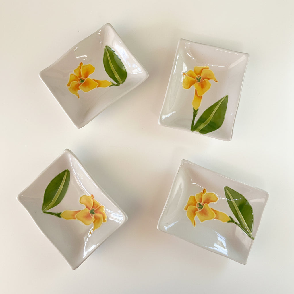 A set of four hand-painted ceramic sauce dishes with a floral pattern, displayed on a textured white surface.