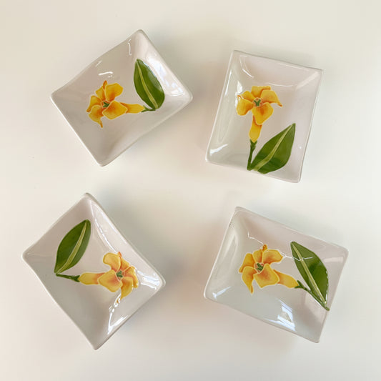A set of four hand-painted ceramic sauce dishes with a floral pattern, displayed on a textured white surface.