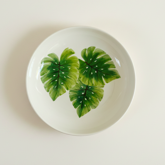 Round ceramic plate with green leaf design on a white background