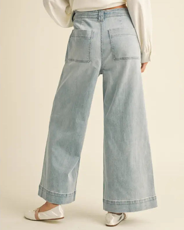 Light blue wide-leg jeans worn by a person on a beige background