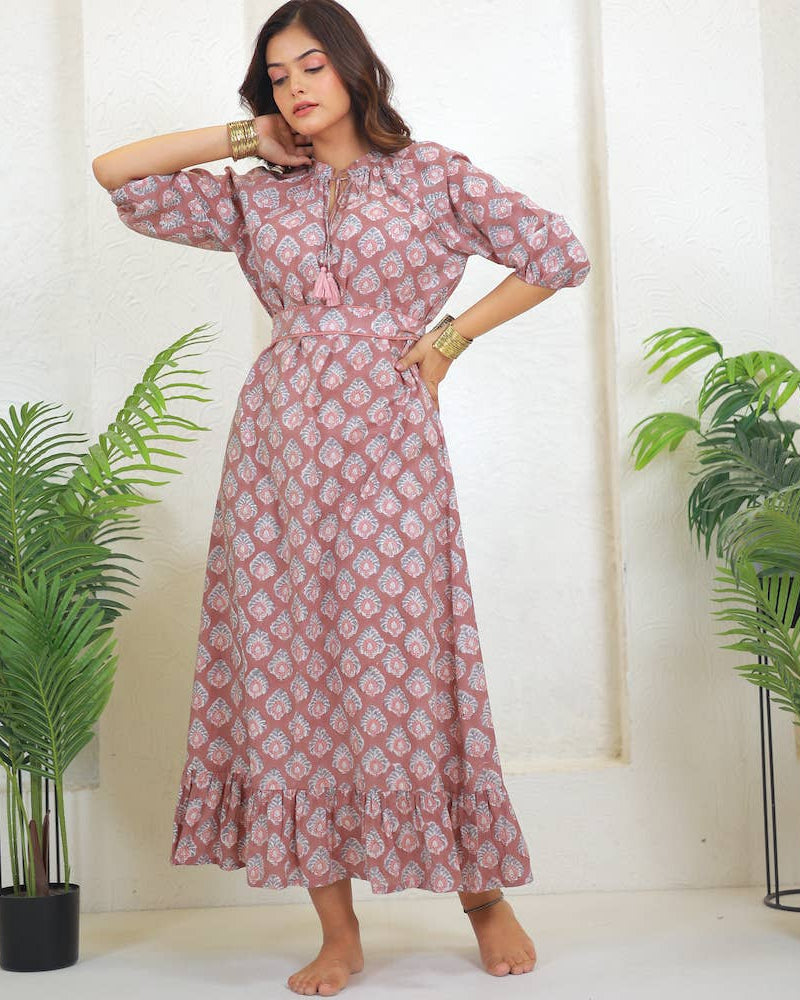 Woman wearing a pink floral dress standing in a room with plants.