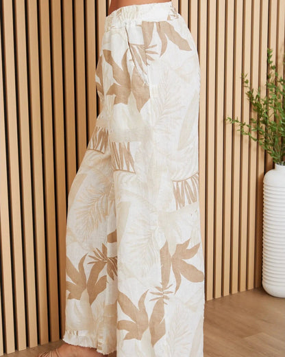 White pants with beige leaf pattern worn by a person indoors.