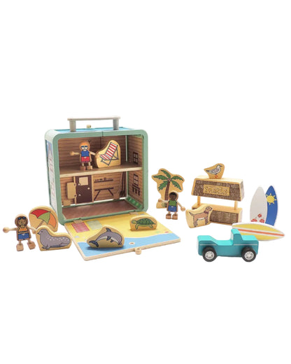 A wooden suitcase toy with a surf shack theme, including surfer figures, surfboards, a dog, a dolphin, and a snack shack