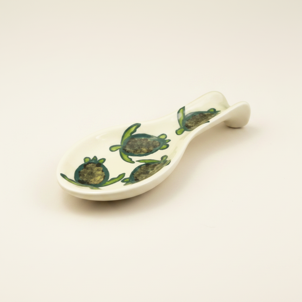 A beige spoon rest with a celadon turtle pattern, hand-painted with multiple turtle designs.