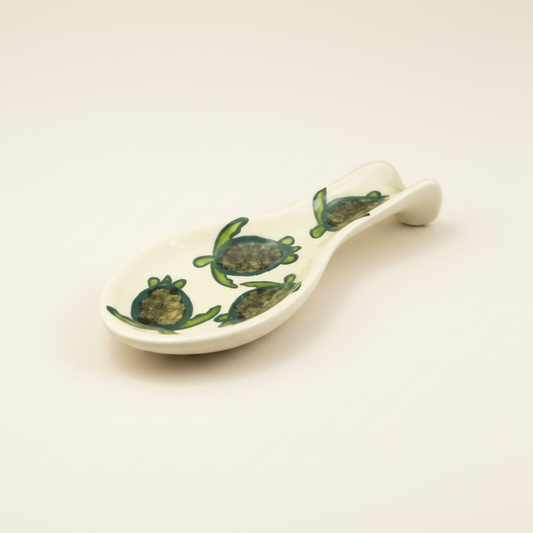 A beige spoon rest with a celadon turtle pattern, hand-painted with multiple turtle designs.